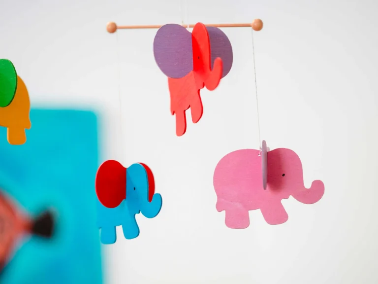 Ein Mobile aus drei Elefanten in blau, rosa und rot.